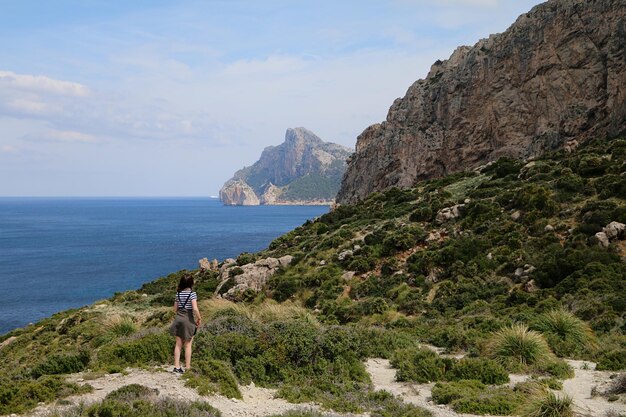 Rear view of woman standing by sea against sky