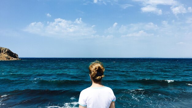 Photo rear view of woman standing by sea against sky