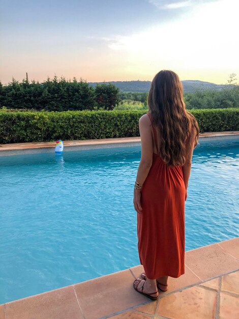 Foto vista posteriore di una donna in piedi vicino alla piscina