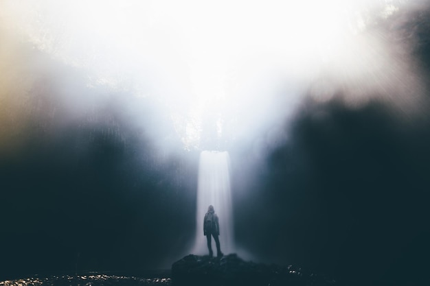 Photo rear view of woman standing by waterfall in foggy weather