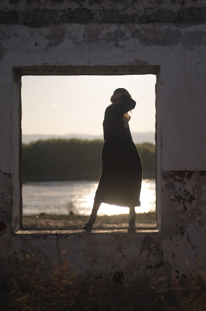 Foto vista posteriore di una donna in piedi vicino alla finestra