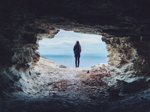 Foto vista posteriore di una donna in piedi all'ingresso della grotta