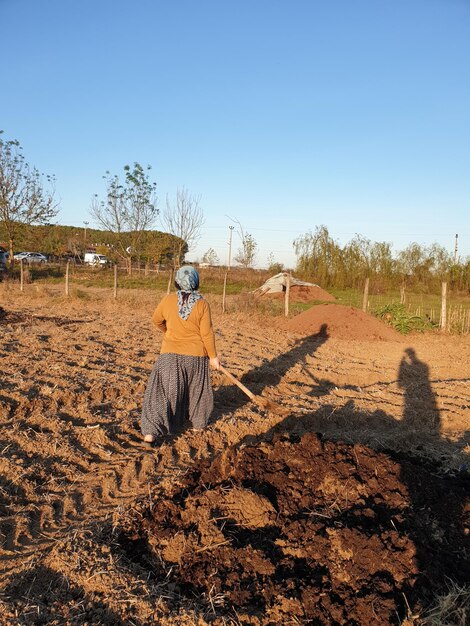 Foto vista posteriore di una donna in piedi sul campo contro un cielo limpido