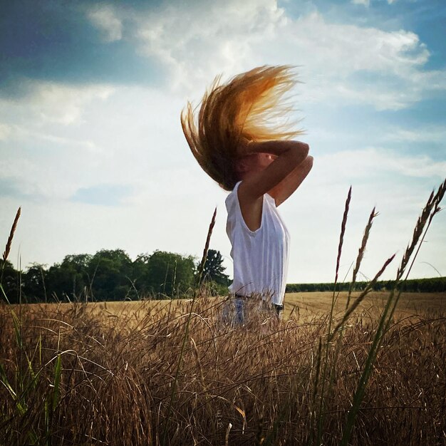 Foto vista posteriore di una donna in piedi sul campo contro il cielo