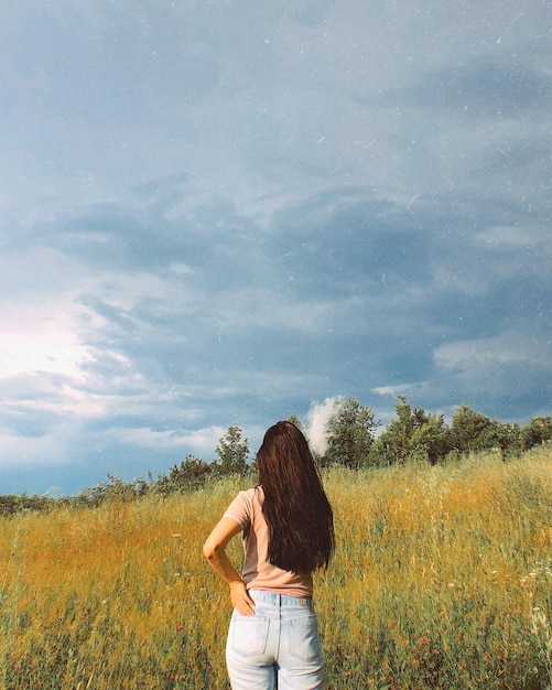 Photo rear view of woman standing on field against sky