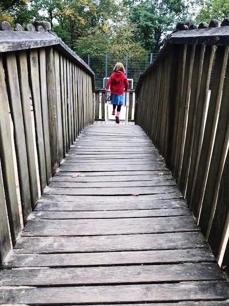 Rear view of woman standing on footbridge