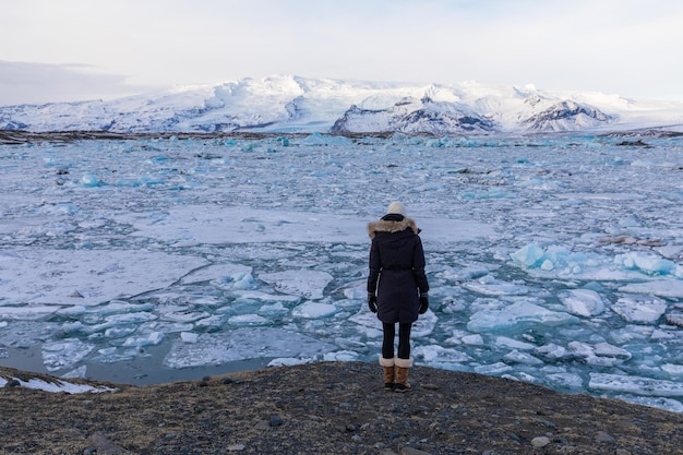 Rear view of woman standing in front of gjacier lagoon against sky