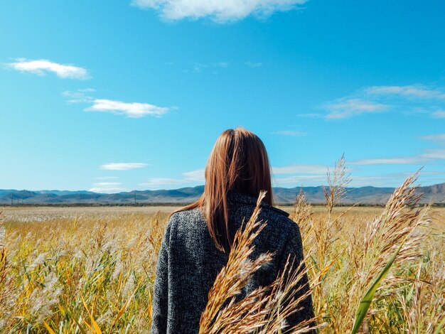 Rear view of woman standing on land against sky