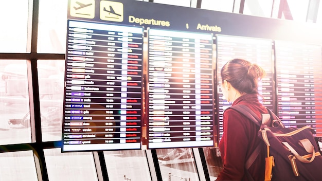 Foto vista posteriore di una donna in piedi che guarda la scheda di partenza dell'aeroporto