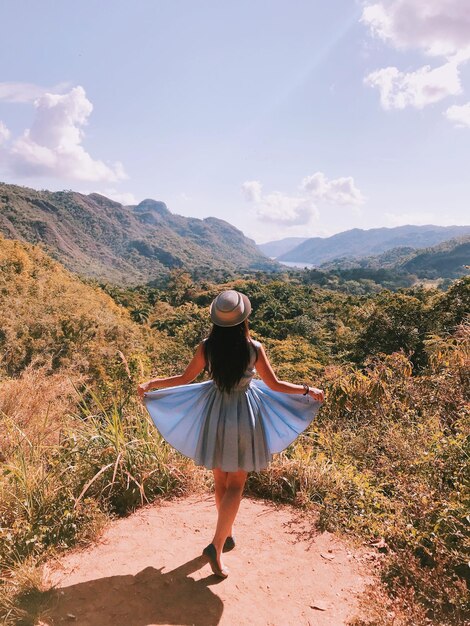 Rear view of woman standing on mountain against sky