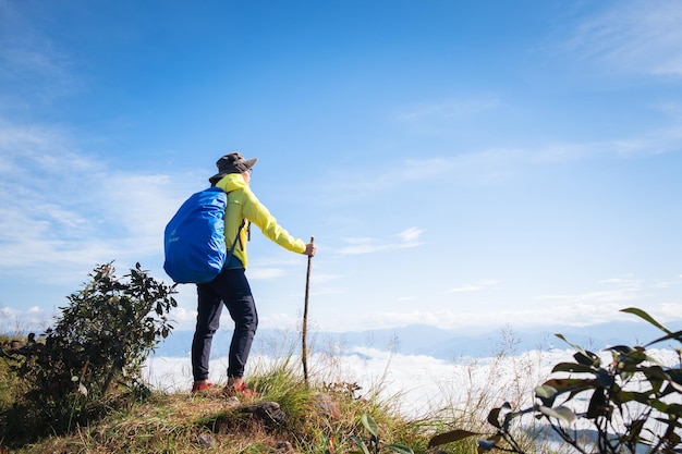 空の向こうの山の上に立っている女性の後ろの景色
