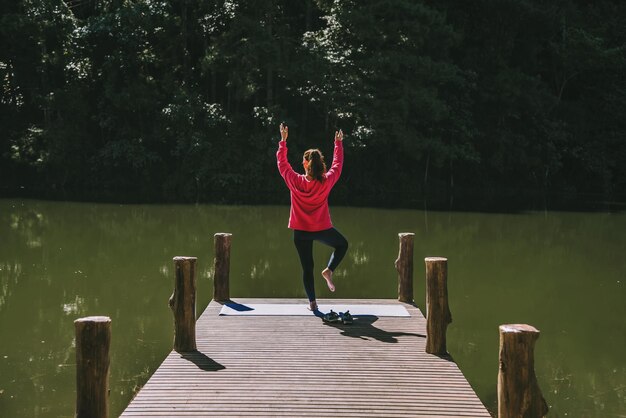 Photo rear view of woman standing on pier over lake