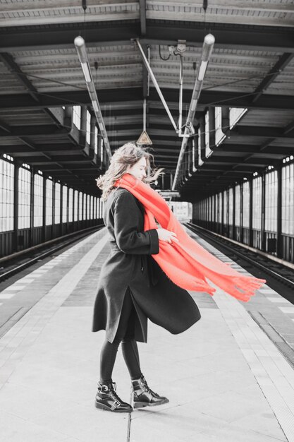 Foto vista posteriore di una donna in piedi sulla piattaforma della stazione ferroviaria