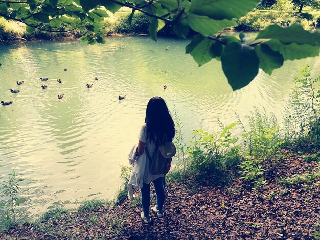 Foto vista posteriore di una donna in piedi sulla riva del fiume