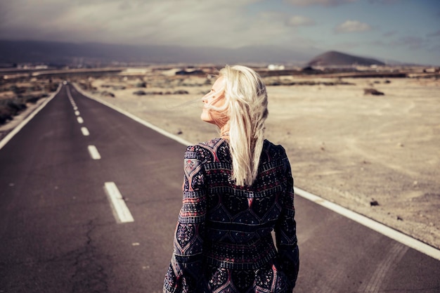 Foto vista posteriore di una donna in piedi sulla strada contro il paesaggio