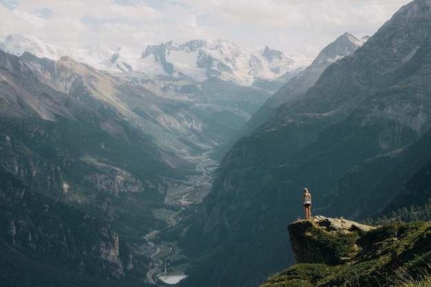 Rear view of woman standing on rock against mountains