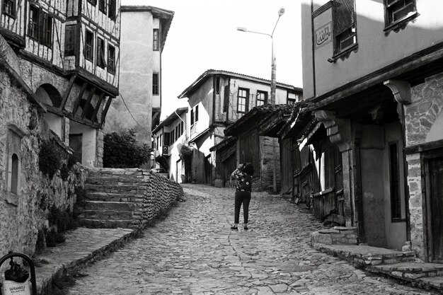 Foto vista posteriore di una donna in piedi sulla strada tra gli edifici