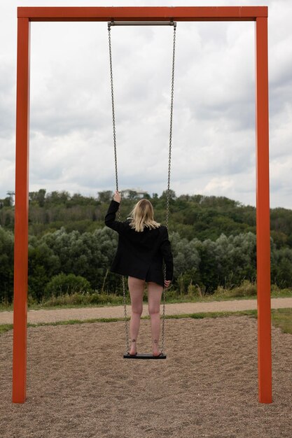 Foto vista posteriore di una donna in piedi su un altalena contro il cielo