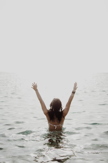 Foto vista posteriore di una donna che nuota in mare contro un cielo limpido