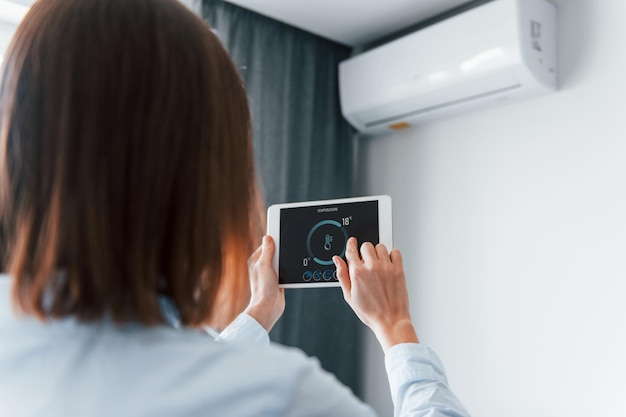 Rear view of woman that is indoors controlling smart home technology