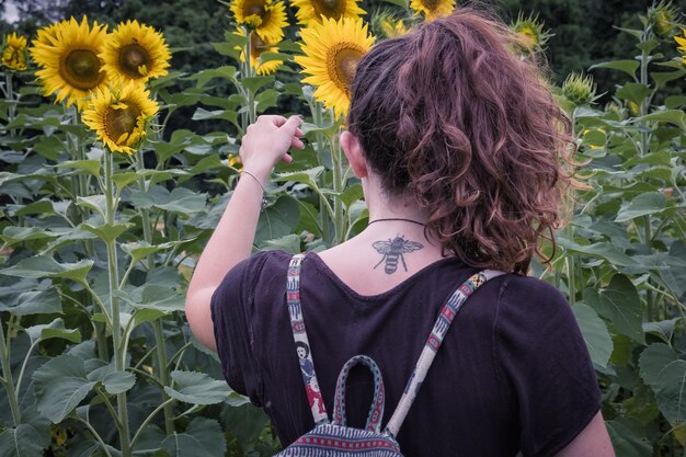 Photo rear view of woman touching sunflower at field