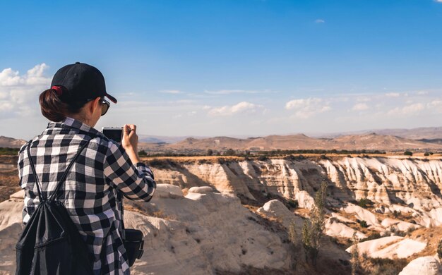 Rear view of woman tourist photographing canyon in cappadocia turkey