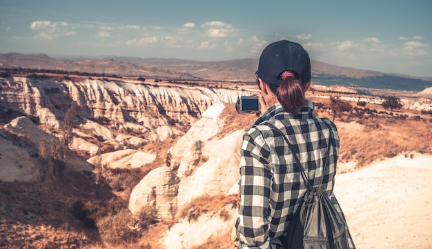 Rear view of woman tourist photographing canyon in cappadocia turkey