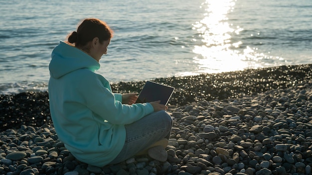 Rear view of woman using mobile phone at beach