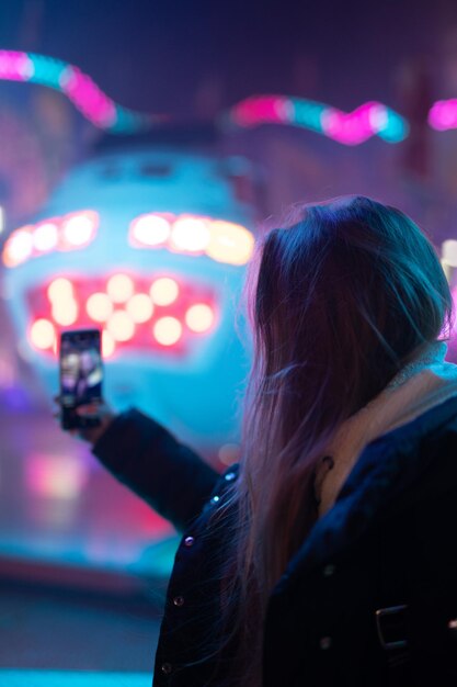 Rear view of woman using mobile phone at night