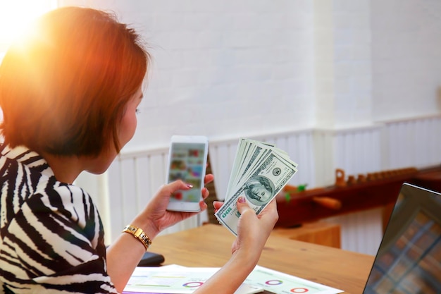 Rear view of woman using mobile phone at table