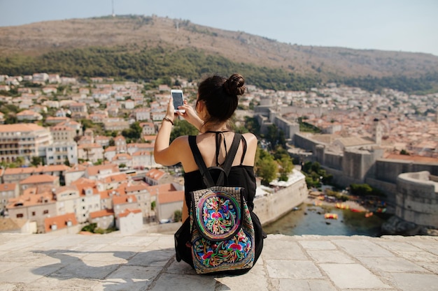 rear view of woman using mobile phone on wall