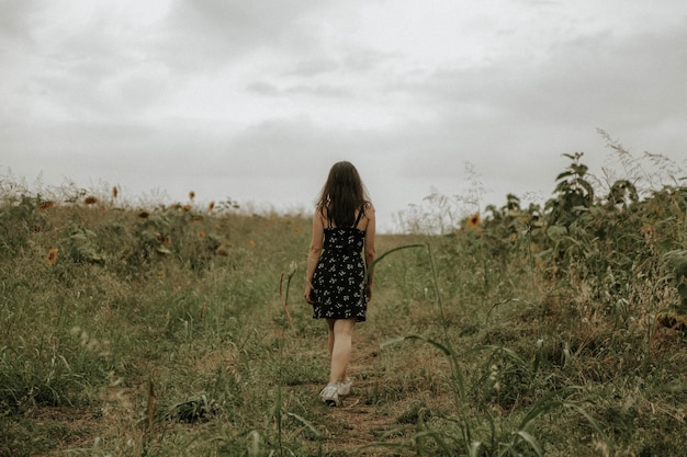 Rear view of woman walking amidst plants on field