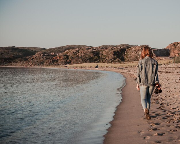 Photo rear view of woman walking at beach against clear sky