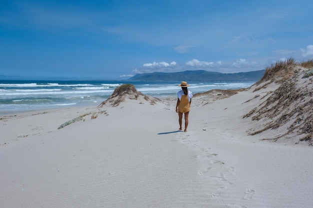 Rear view of woman walking at beach against sky