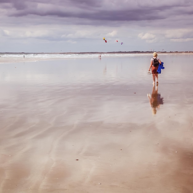 Foto vista posteriore di una donna che cammina sulla spiaggia