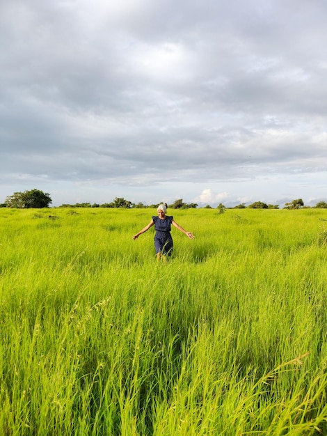 Rear view of woman walking on field against sky