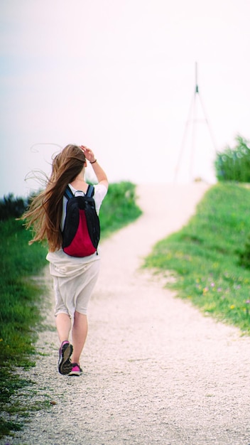 rear view of woman walking on footpath against sky