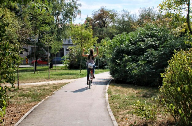 Rear view of woman walking on footpath amidst trees