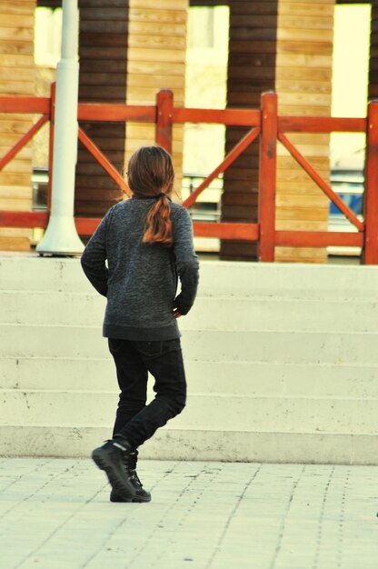 Rear view of woman walking on footpath