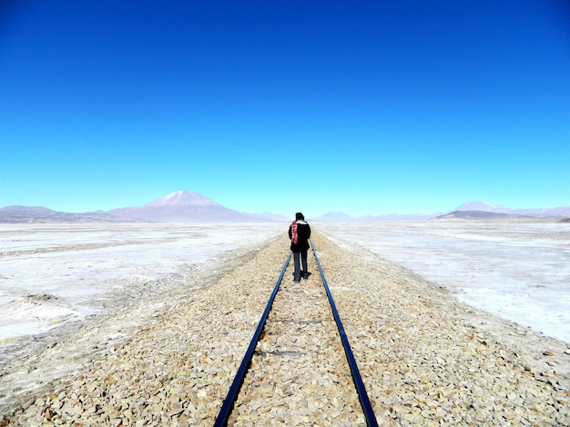 Foto vista posteriore di una donna che cammina sul paesaggio contro un cielo blu limpido