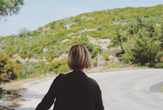 Foto vista posteriore di una donna che cammina sulla strada di montagna