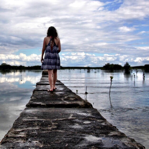 Rear view of woman walking on pier at river