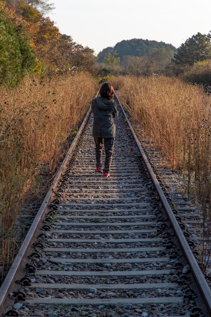 鉄道線路を歩く女性の後ろの景色