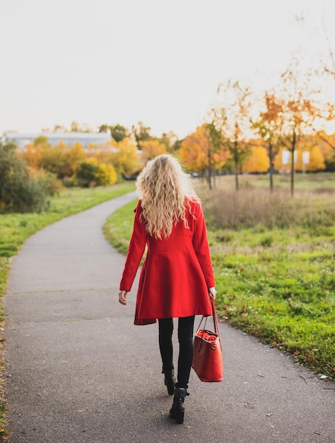 Foto vista posteriore di una donna che cammina su un ombrello rosso