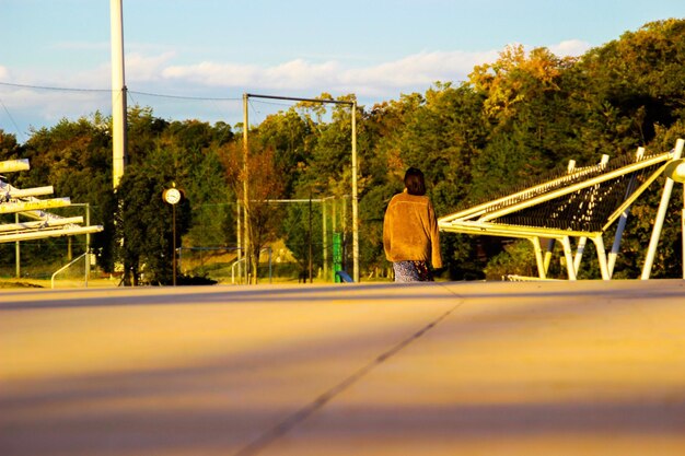 Photo rear view of woman walking on road against trees in sunny day