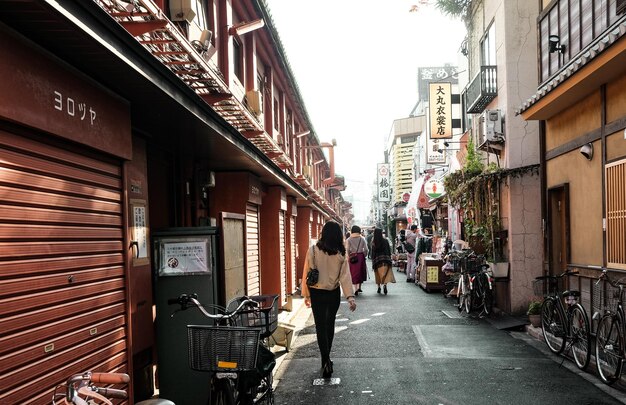 Photo rear view of woman walking on street amidst buildings in city