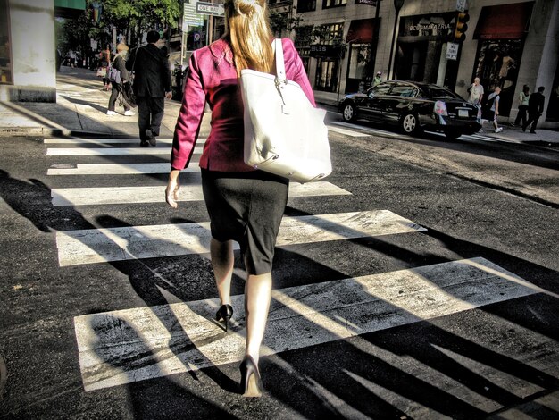 Photo rear view of woman walking on zebra crossing in city