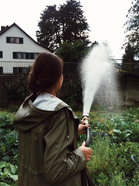 庭に水を注ぐ女性の後ろの景色