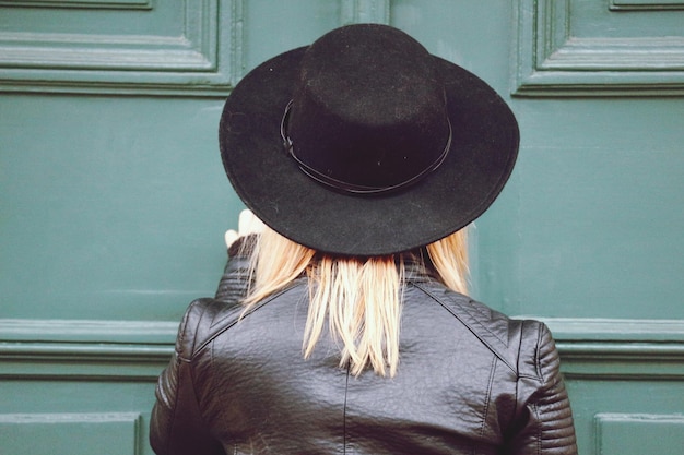 Photo rear view of woman wearing hat against door