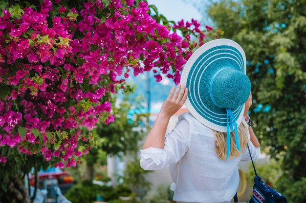 Foto vista posteriore di una donna che indossa un cappello contro le piante